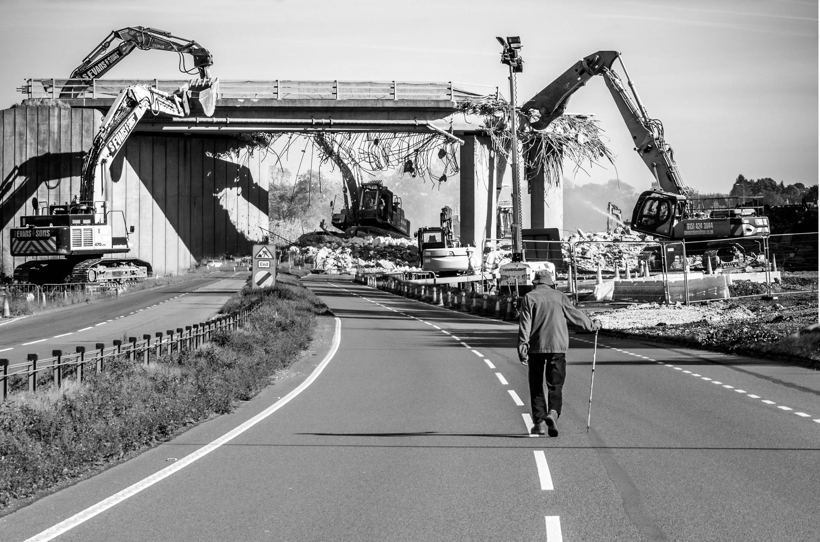 An old man walking in a demolition landscape